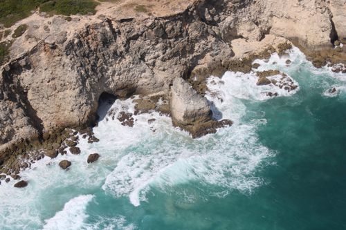 Free A stunning aerial shot of rugged coastal cliffs and turquoise waves crashing against rocks. Stock Photo