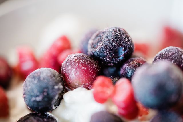 Frosty frozen blueberries and red berry pieces resting on a creamy white base