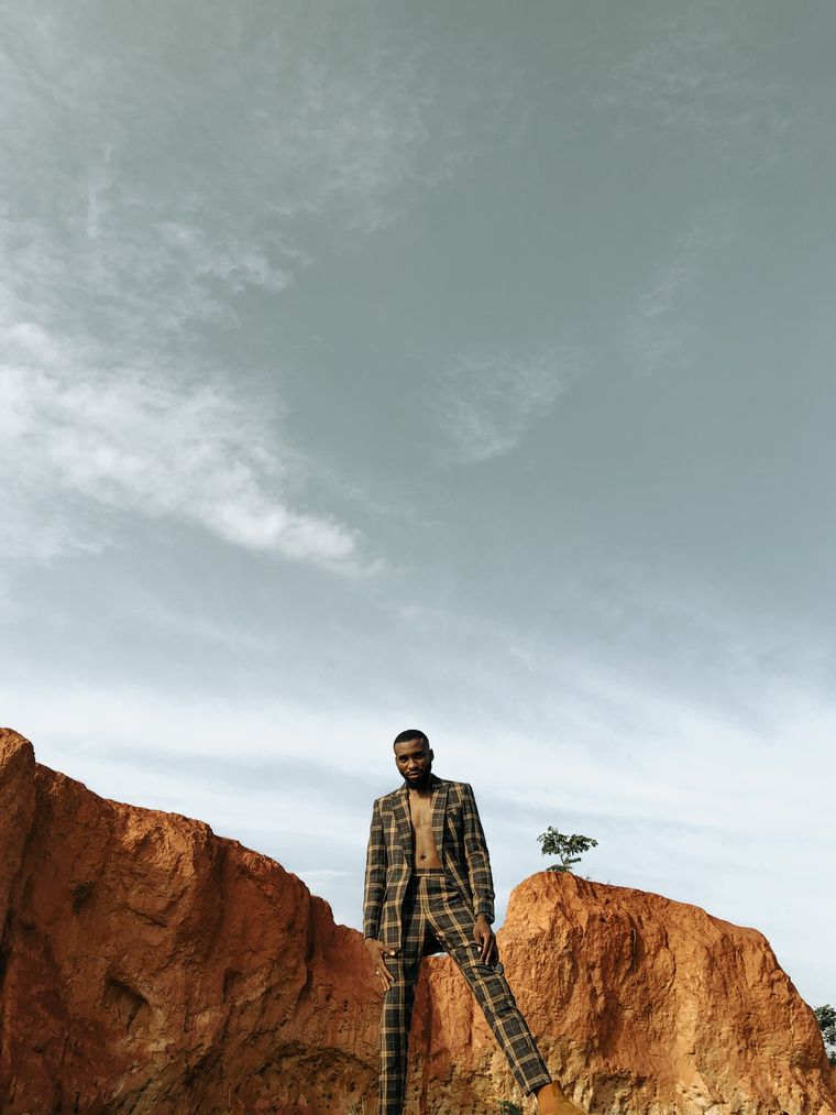 Model in a tailored check suit on a ridge under open sky — photo by Jonathan Yakubu on Pexels