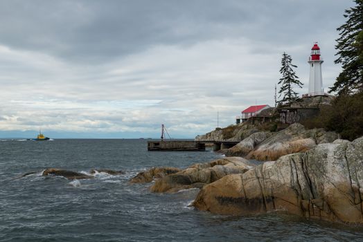 A serene view of Vancouver's iconic lighthouse and rocky coastline on a cloudy day.
