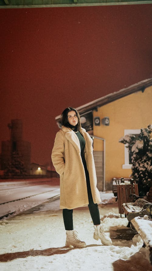 Woman in a Warm Coat Standing on the Sidewalk 