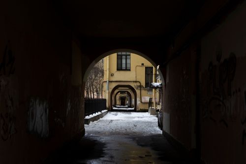 Free A dark urban alleyway covered in snow, framed by architectural arches. Stock Photo