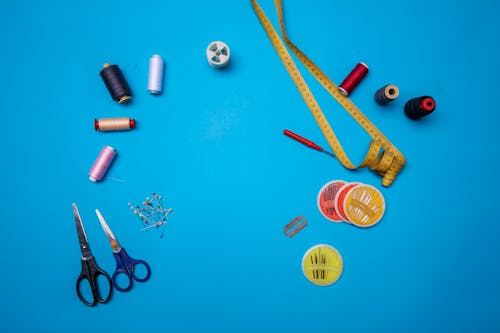 Top View of Sewing Supplies Lying on Blue Background 