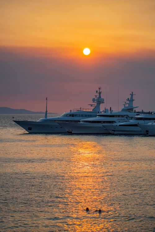 Free Two yachts anchored at sunset in Mikonos, Greece, creating a serene vacation vibe. Stock Photo
