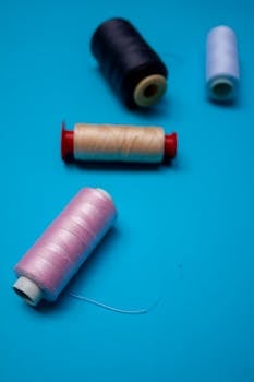 Close-up of colorful sewing threads on a blue surface.