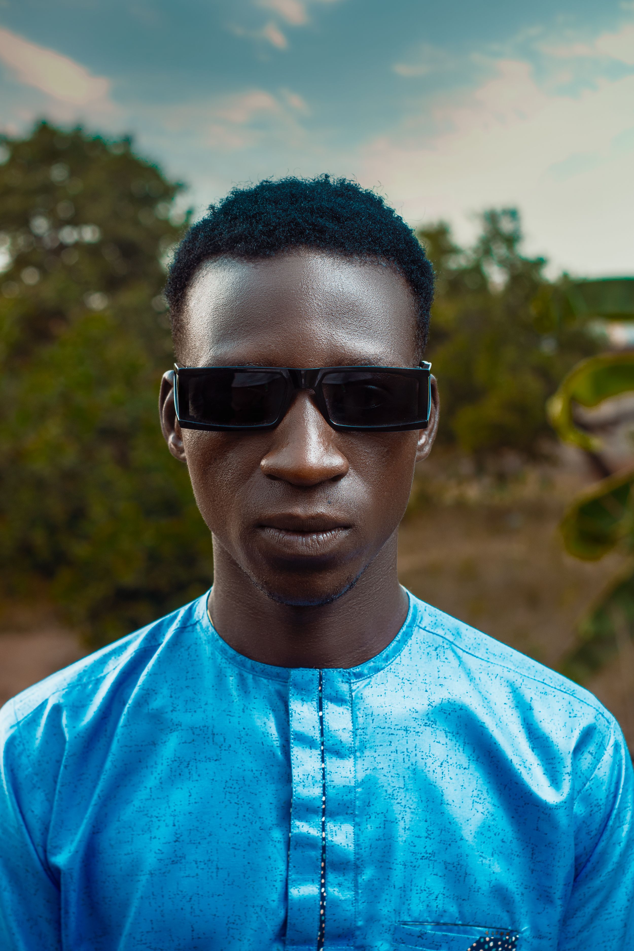 Portrait of a Man in a Blue Shirt and Sunglasses Standing Outside ...