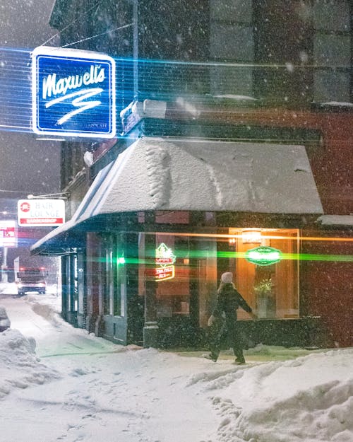 Woman Walking near Cafe in Winter at Night