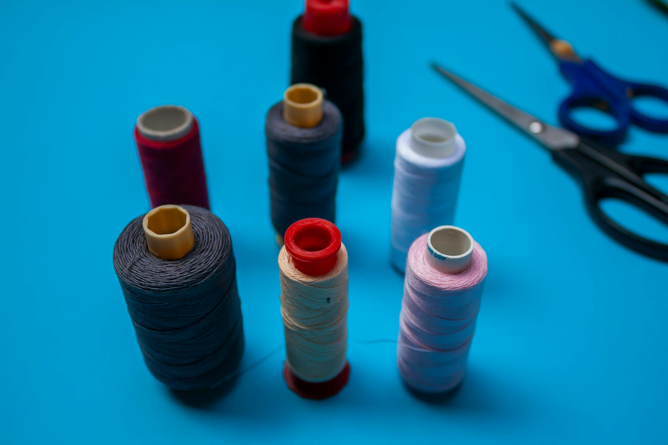 Close-up of Threads and Scissors Lying on Blue Background · Free Stock ...