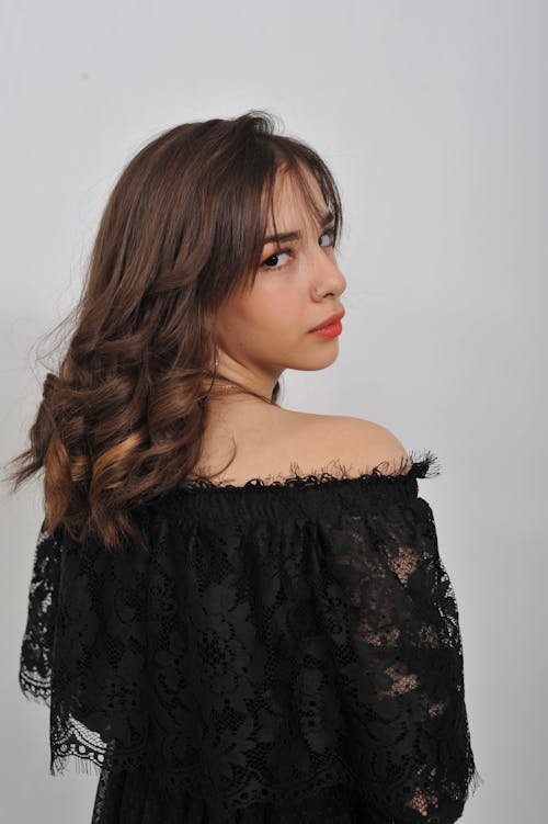 Studio Shot of a Young Woman in a Black, Lace Dress Looking over Her Shoulder
