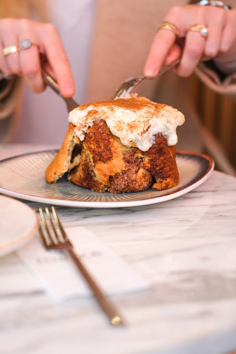 Hands Eating Cinnamon Bun With Fork