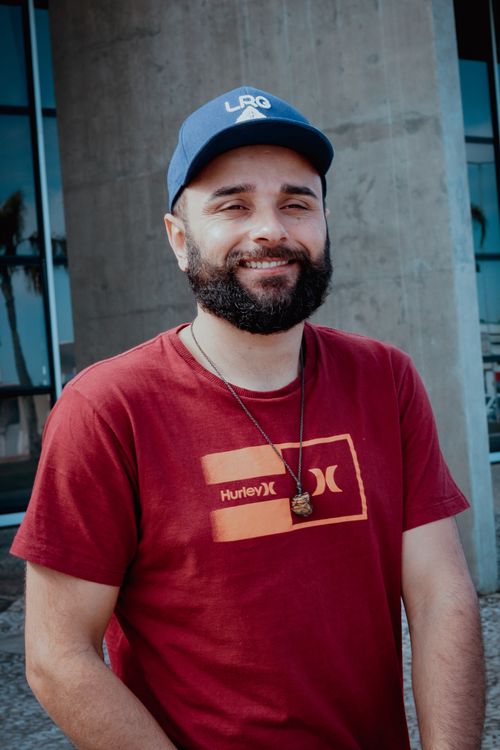 Free Close-up of a smiling bearded man in a blue cap and red shirt standing outdoors. Stock Photo