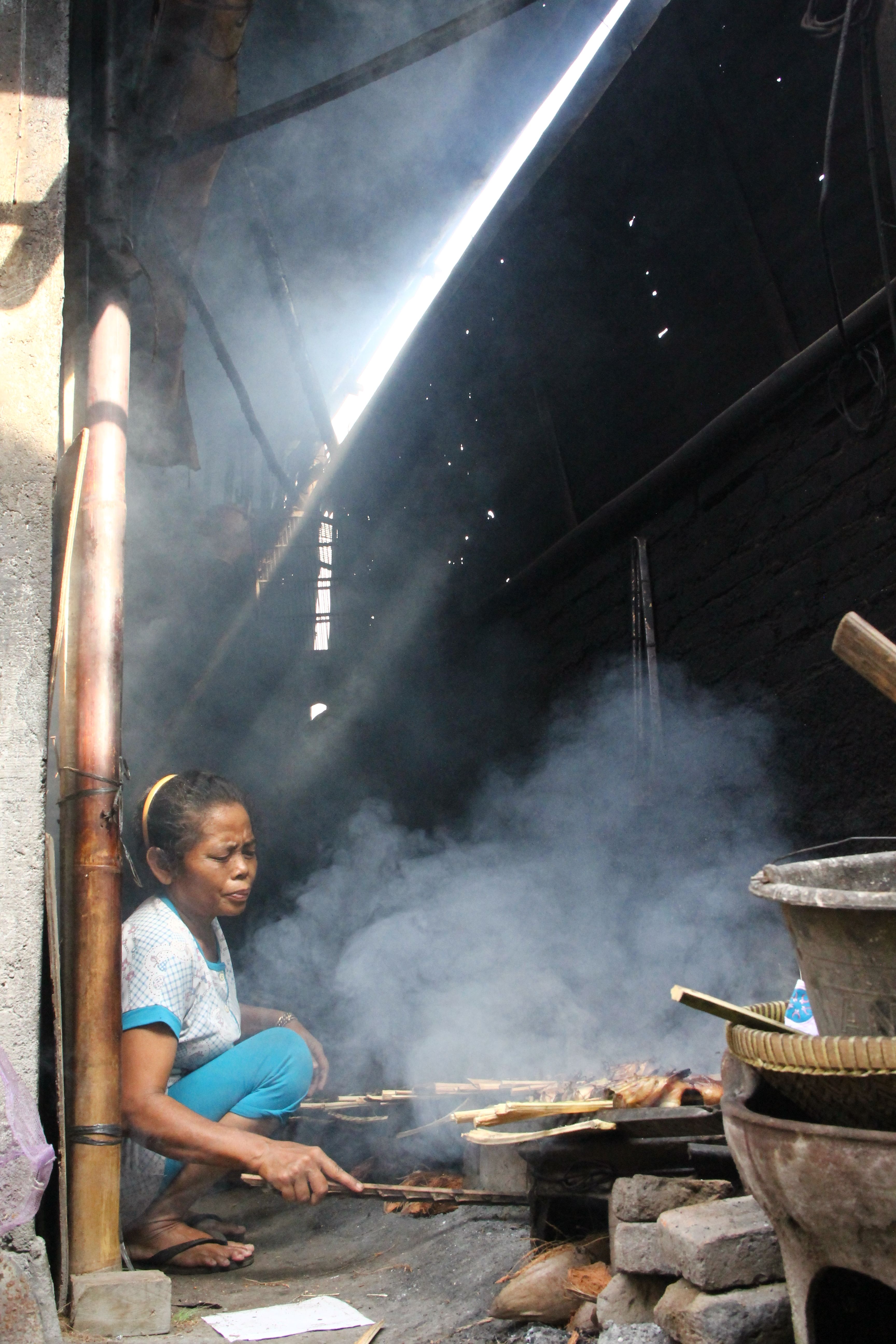 Woman Crouching in Ground Cooking