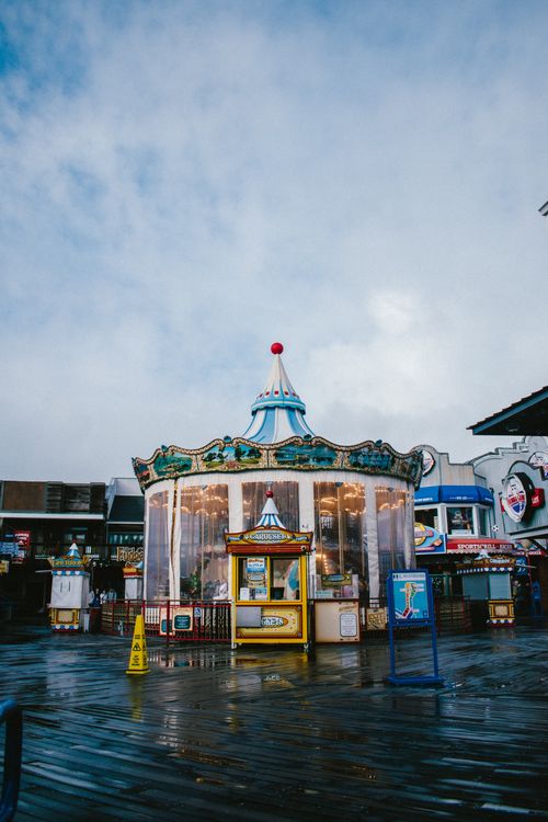 Free Vibrant carousel under a cloudy sky at San Francisco's iconic pier, creating a nostalgic amusement park scene. Stock Photo
