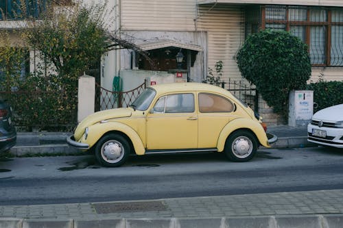 A Yellow Volkswagen Beetle Parked on the Side of a Street 