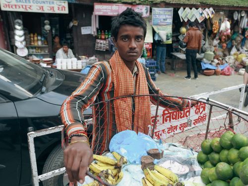 Free A street vendor with bananas and limes at a bustling local market. Stock Photo