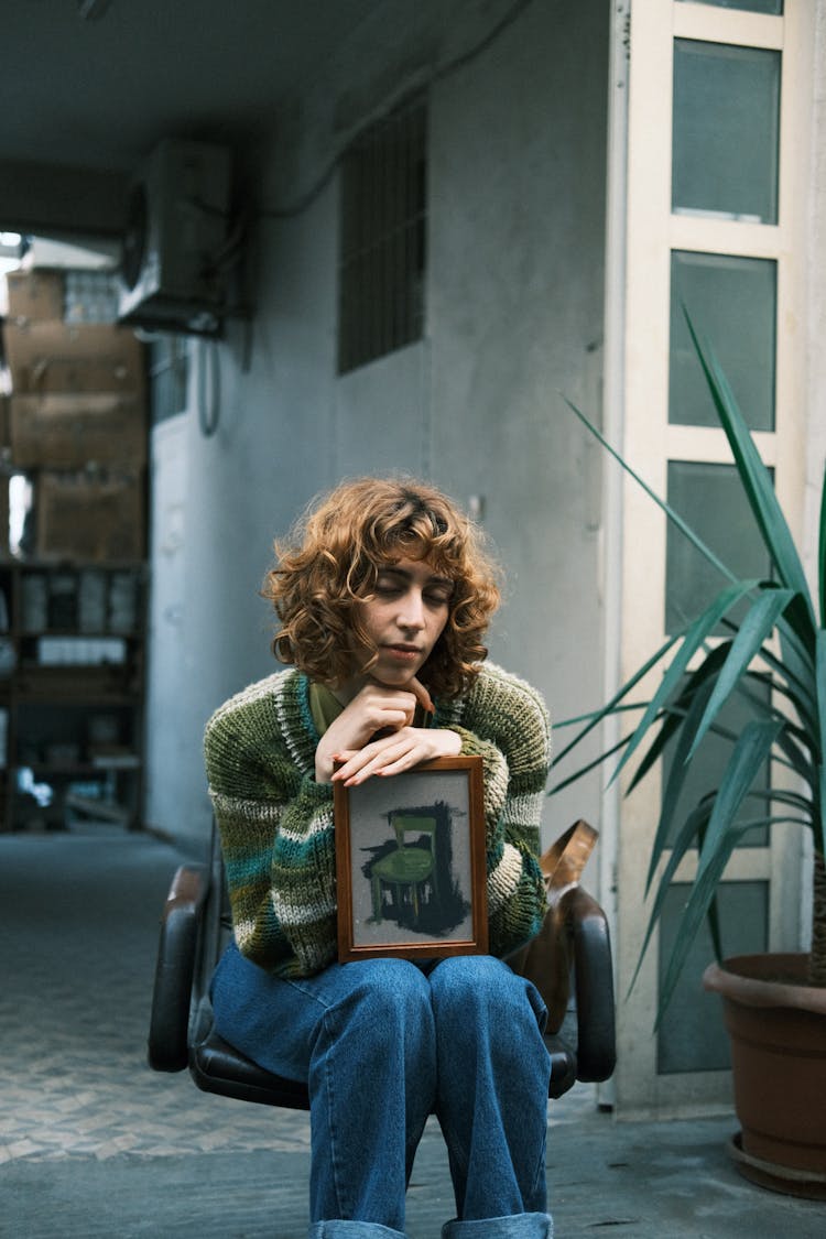 Woman Sitting Outdoor On The Chair With Framed Picture