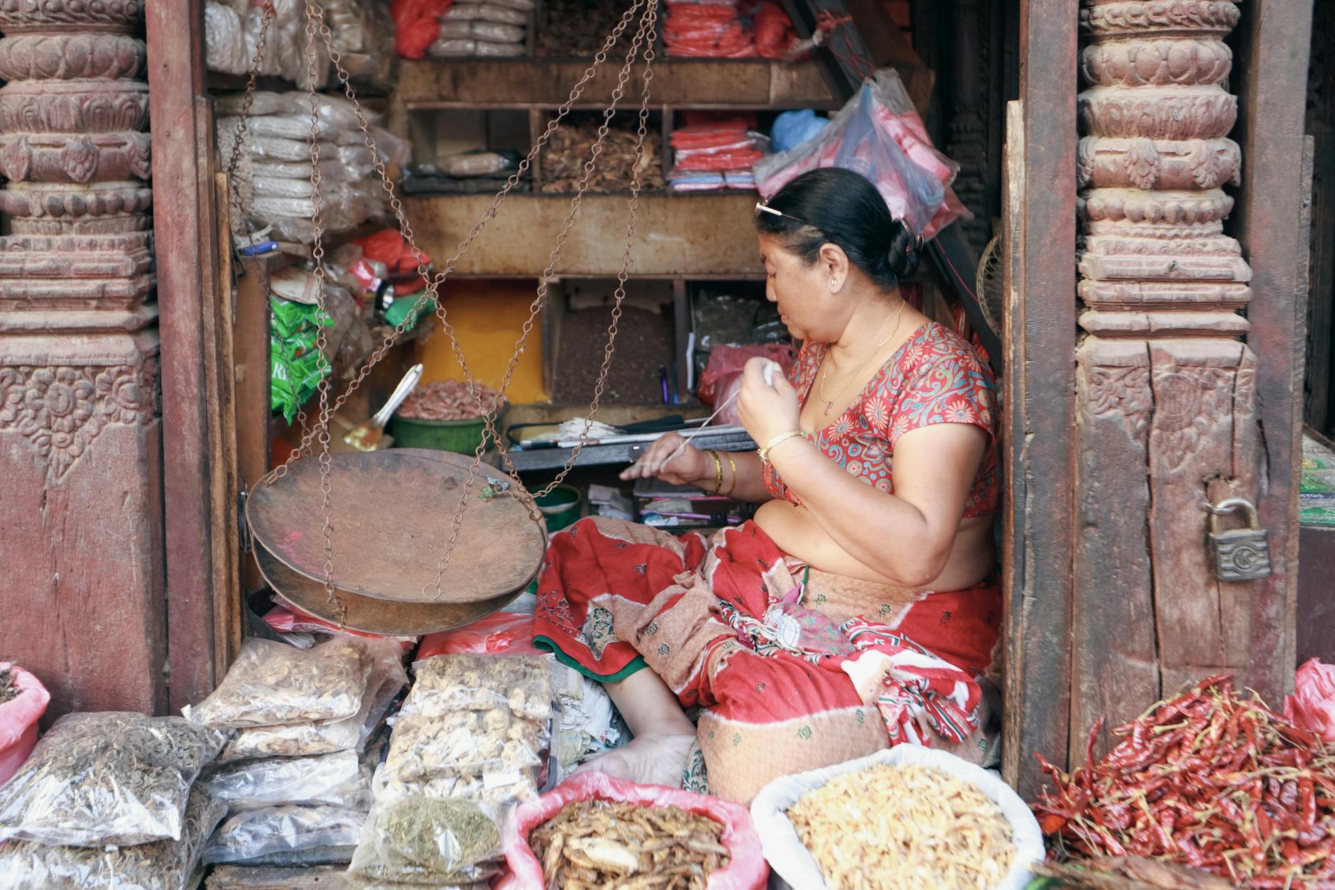 A woman selling traditional dried goods in an outdoor market, showcasing cultural heritage.