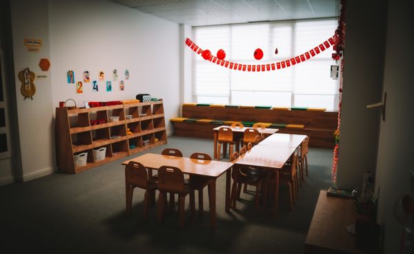 Kindergarten classroom with low wooden tables and shelving, photo by Batuhan Kocabaş on Pexels