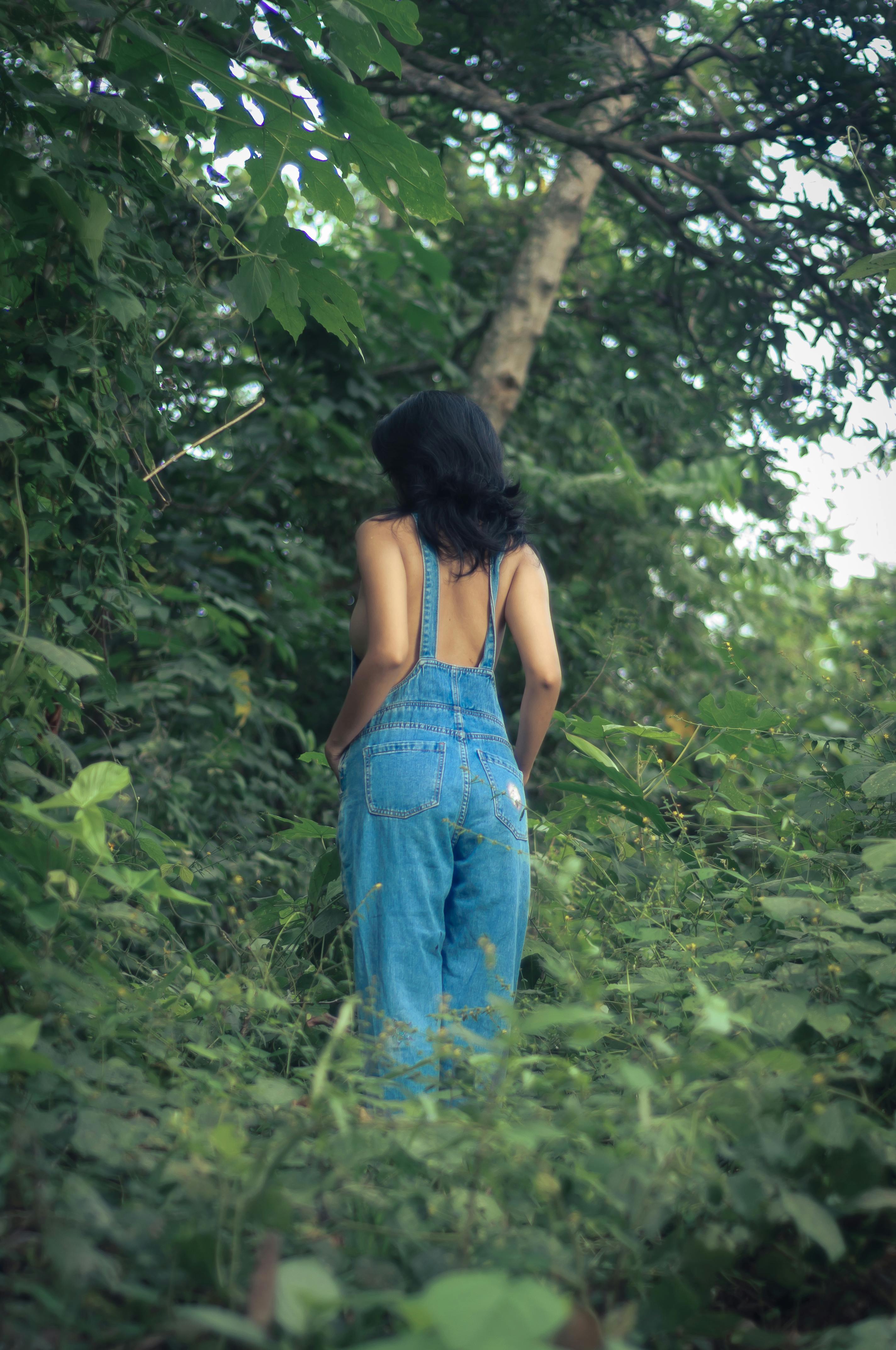 Back View of a Woman in Denim Overalls Standing in a Forest · Free Stock  Photo
