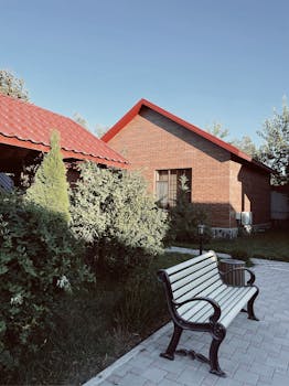 Peaceful garden scene with a bench, house, and clear sky in Azerbaijan.