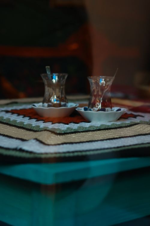 Free Two clear glass tea cups on a vibrant, patterned tablecloth, with a warm ambient setting. Stock Photo