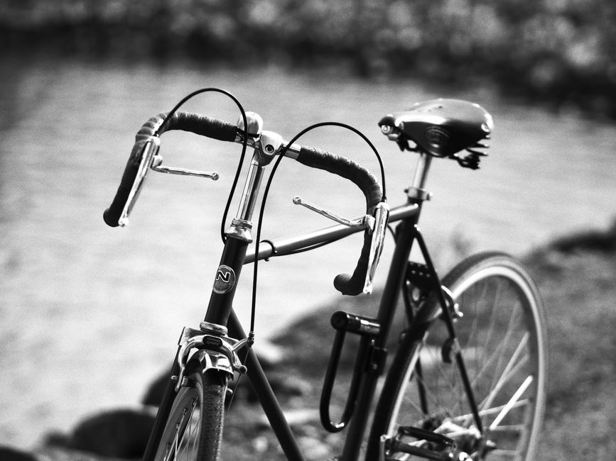 Retro bicycle with drop handlebars by a waterfront, showcasing vintage style.