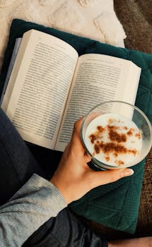 A person enjoys a book and spiced latte for ultimate relaxation at home.