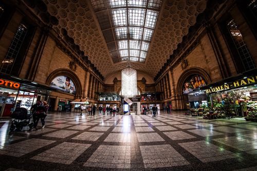 Free Bustling interior of Leipzig railway station with shops and travelers under ornate architecture. Stock Photo