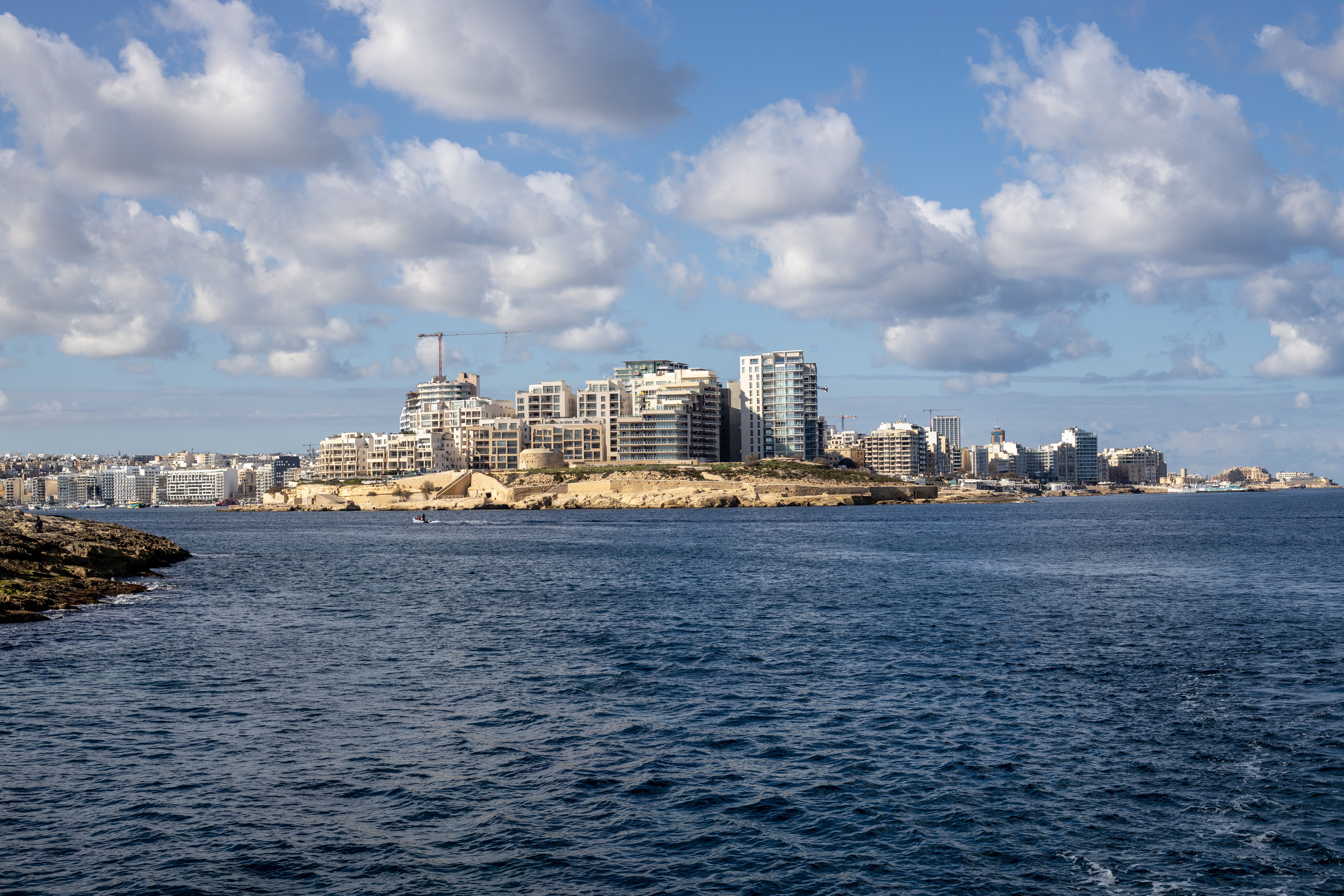 View across the water toward a Maltese coastal city at golden hour