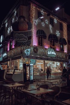 Charming urban cafe adorned with festive Christmas lights, offering a warm atmosphere at night.