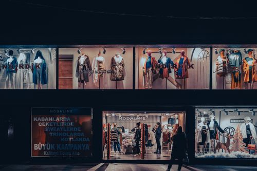 Free Illuminated fashion store window with mannequins and dramatic lighting at night. Stock Photo