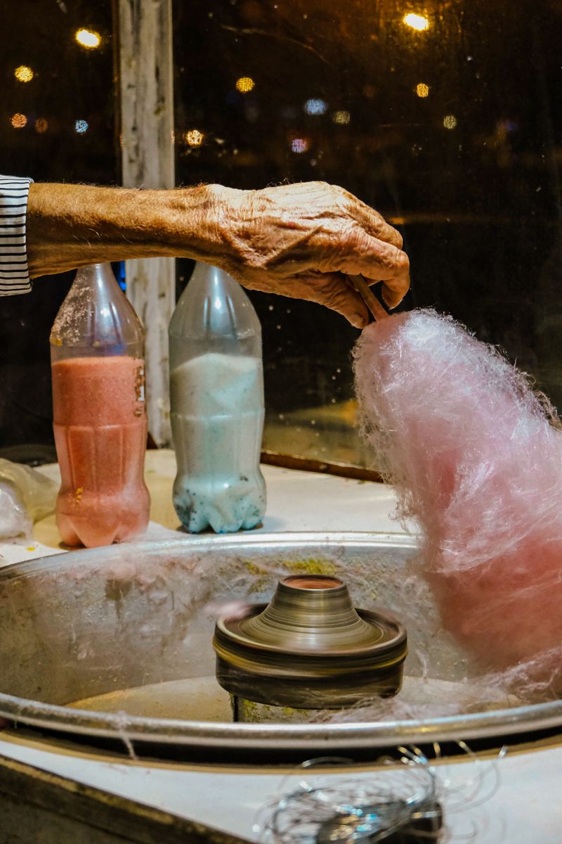 A person making cotton candy by hand at a stand