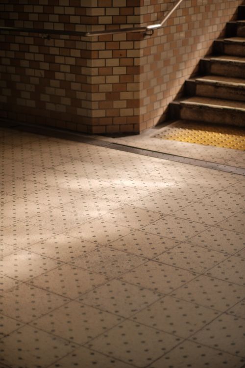 Free Dramatic lighting in an underground tunnel with brick walls and tiled floor, creating a moody urban scene. Stock Photo