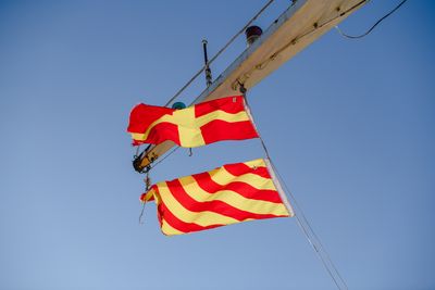 Striped signal flags flying against a clear sky, photo by Suki Lee on Pexels