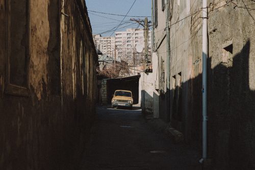 Free Vintage car parked in a shadow-filled urban alley with retro vibes. Stock Photo