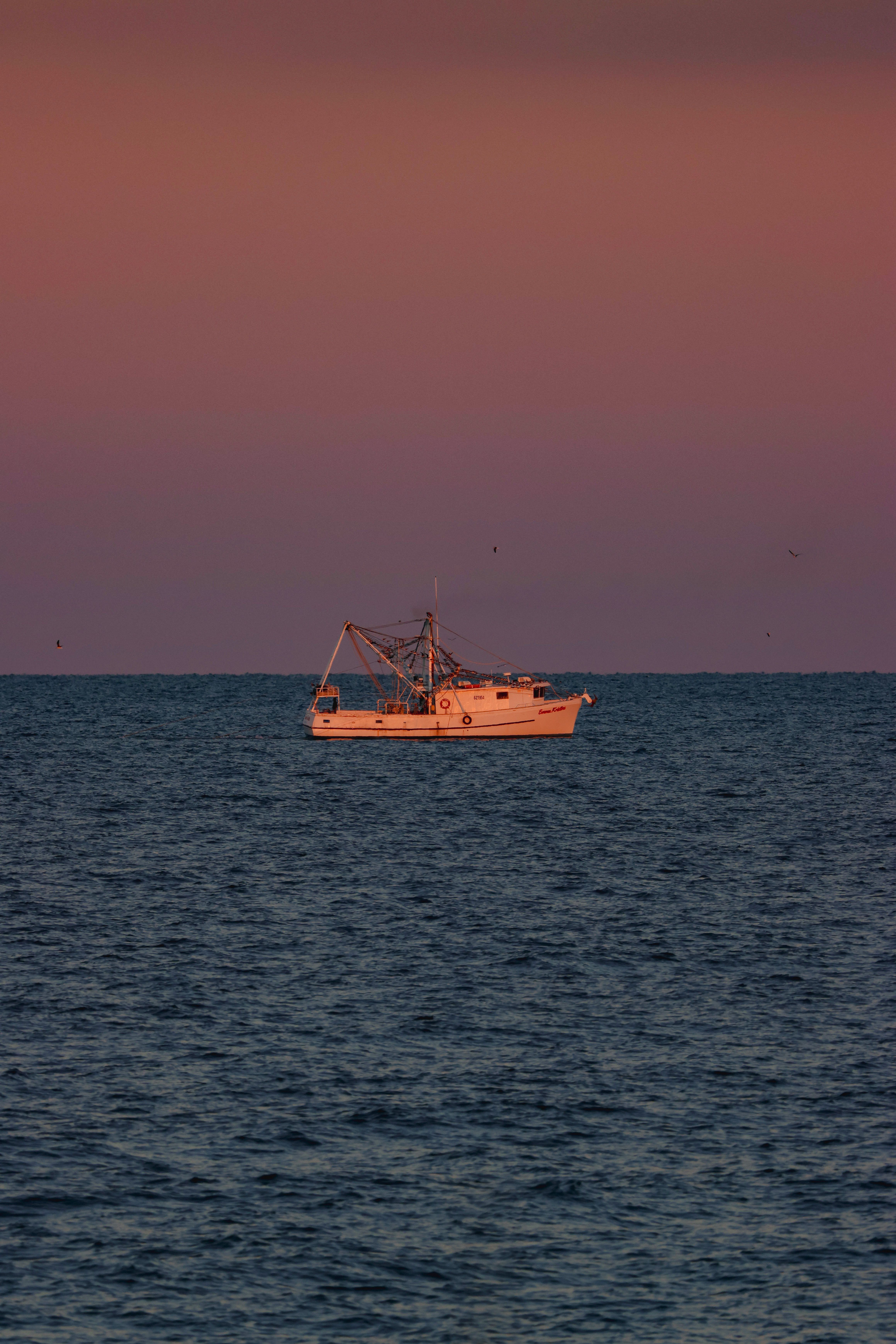 Photo of a Fishing Boat on a Sea at Sunset · Free Stock Photo