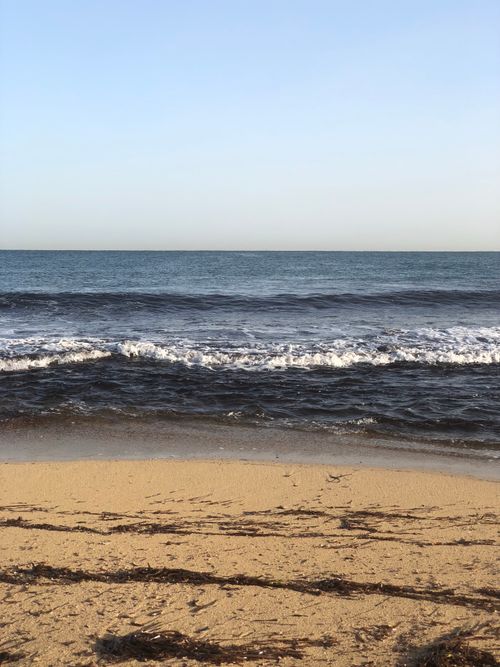 Free Peaceful Libyan beach scene with waves gently crashing onshore under a clear sky. Stock Photo