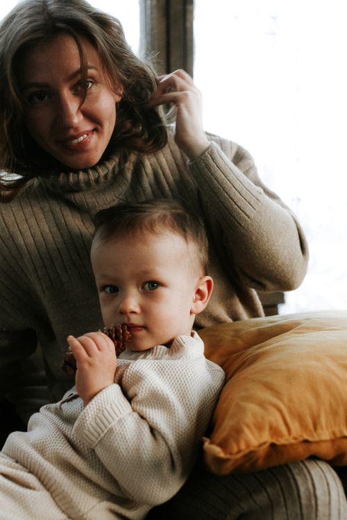 Free Warm indoor portrait of a mother and child sharing a cozy moment in an armchair. Stock Photo