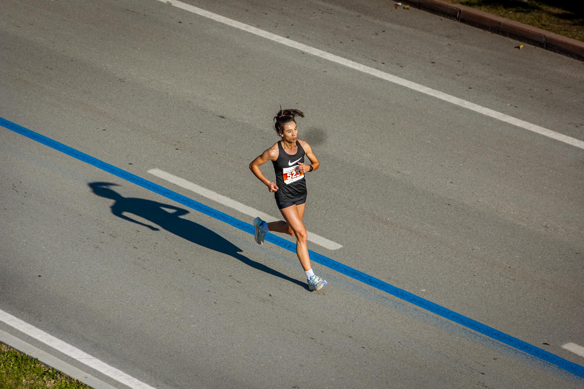 Aerial view of a woman running in a marathon on a city street, capturing endurance and athleticism.