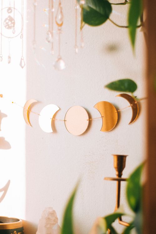 Free Elegant bohemian wall decor featuring gold and white moon phases in a sunlit room. Stock Photo
