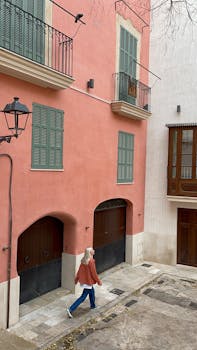 Woman walking along a vibrant street in Palma, with colorful facades and typical Spanish architecture.