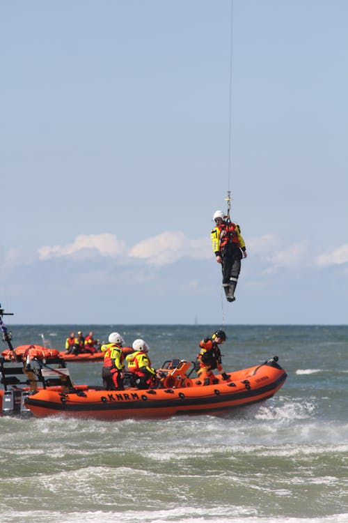 A Water Rescue Team in Rescue Crafts and a Man Lifted on a Line over the Water 