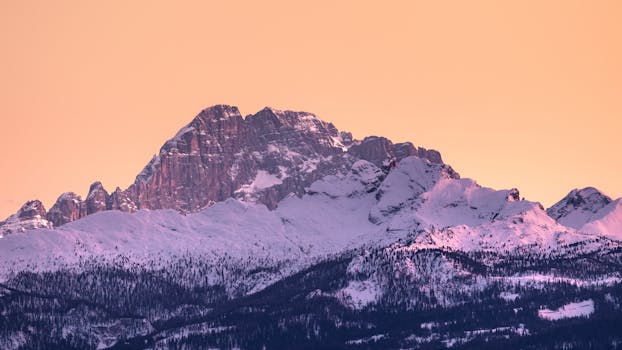 Captivating view of a snow-covered mountain peak at sunrise, showcasing winter beauty.
