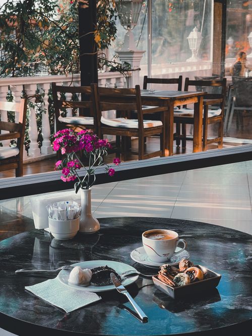 Free Capturing a serene café scene with coffee, pastries, and vibrant flowers on a sunny day. Stock Photo