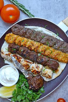 Delicious grilled meat kebabs served with pita bread, fresh herbs, and yogurt sauce.
