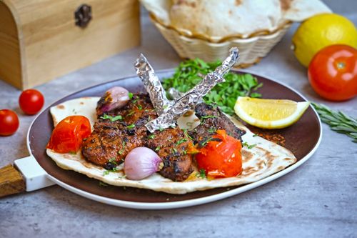 Free Succulent grilled meat on flatbread with vegetables and lemon on a rustic table. Stock Photo