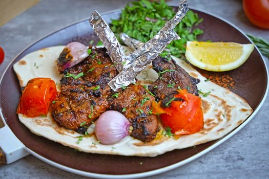 Delicious grilled kebabs served with veggies and lemon on flatbread, perfect for lunch or dinner.