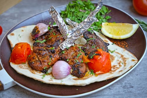 Free Delicious grilled kebabs served with veggies and lemon on flatbread, perfect for lunch or dinner. Stock Photo