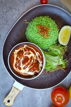 Appetizing rice dish with tomato curry and fresh greens, perfect for a vibrant meal.