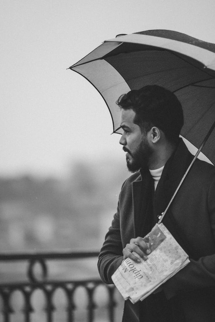 Man Holding An Umbrella And Newspaper